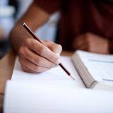 Closeup shot of a young man writing on a note pad